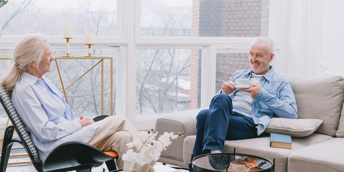 Senior couple relaxing and chatting over tea in a cozy living room.